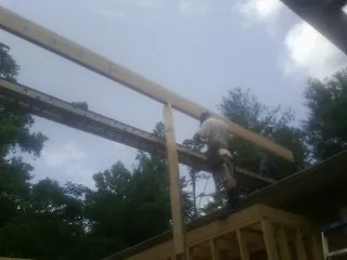 Carpenter setting a ridge beam over a new addition frame — Ice Dam Removal by Roofing Brothers in Bacliff