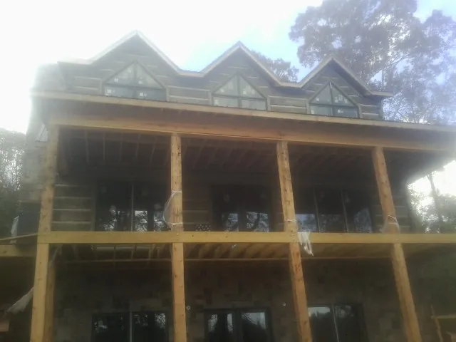 Dormers and porch framing on a large log home under construction — Roof Coating work by our crew in Bacliff