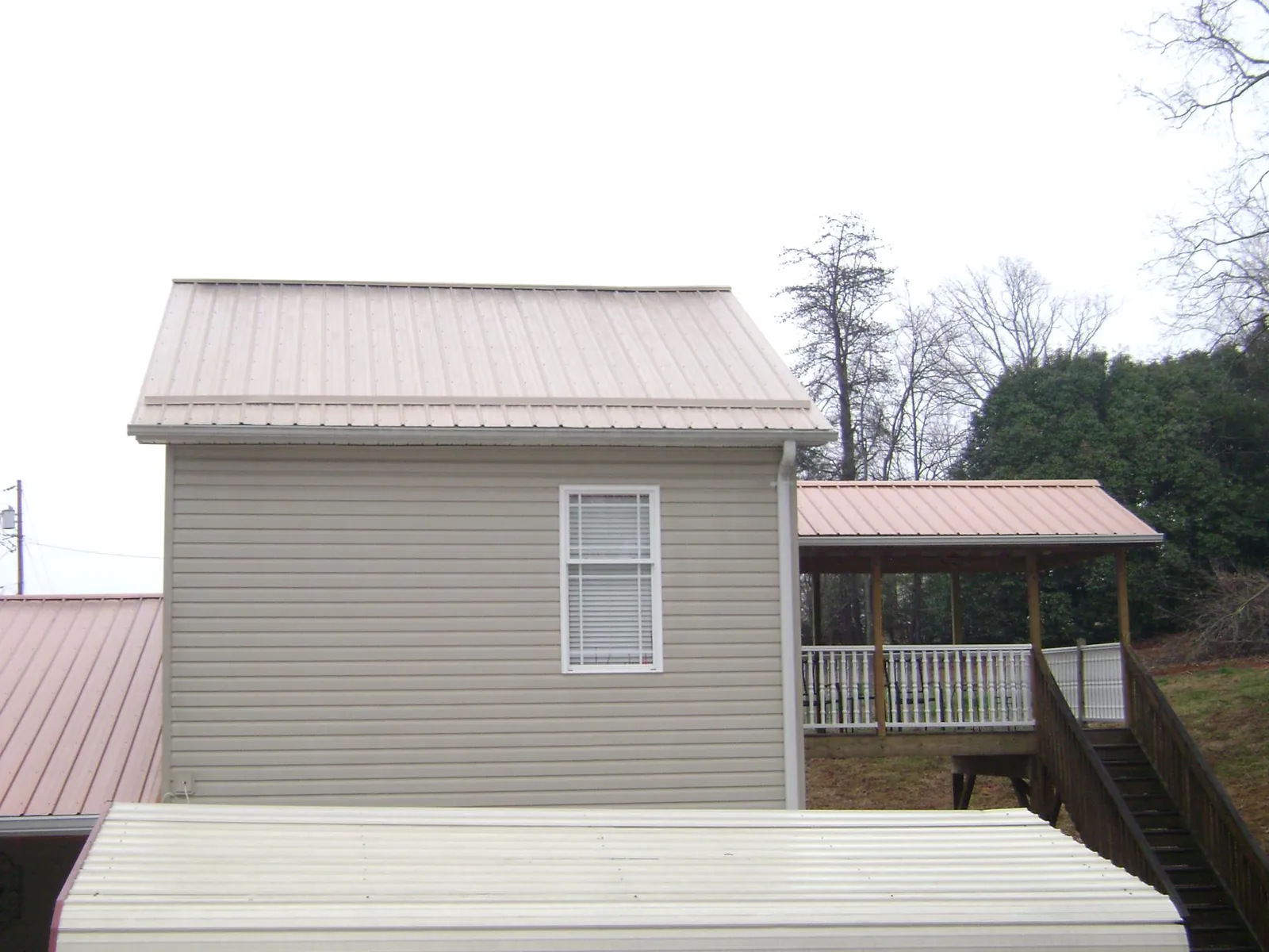 Tan metal roofs on a two story addition and attached porch, from a Roof Replacement job in Bacliff