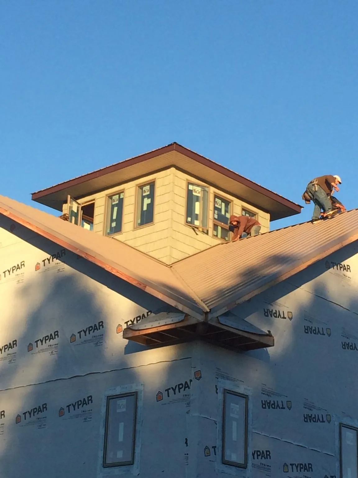 Roofers working around a rooftop cupola on a new metal roof at sunset — Roof Waterproofing in Bacliff by Roofing Brothers